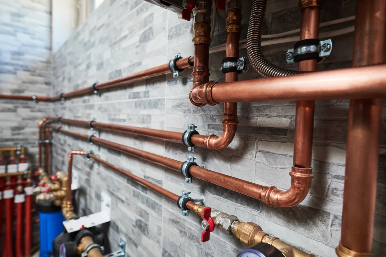 Local technique moderne avec chaudière murale blanche connectée à un ballon d'eau chaude sanitaire cylindrique