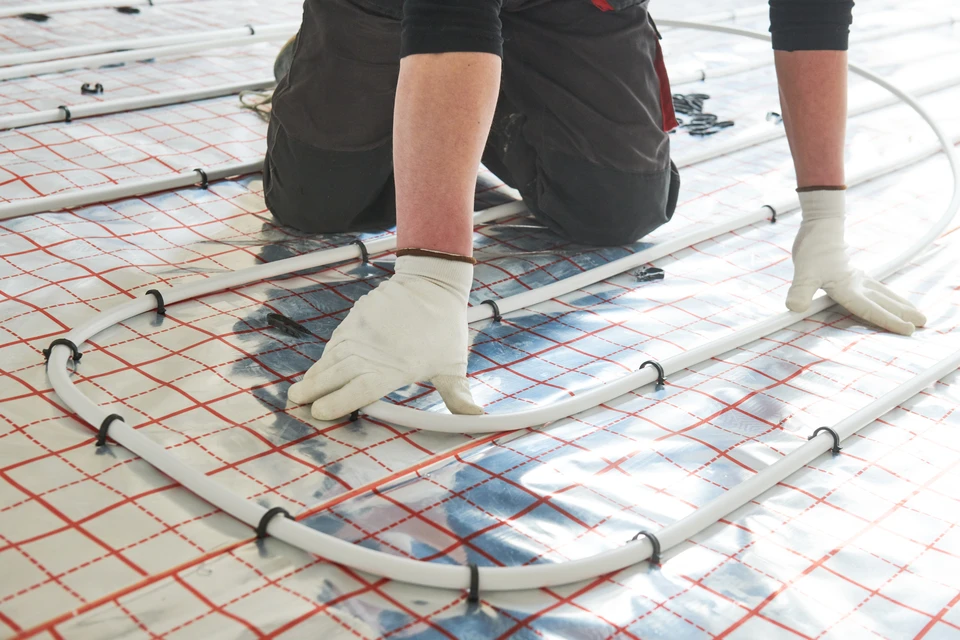 Technicien en plomberie intervenant sur installation de chauffage domestique dans local technique résidentiel