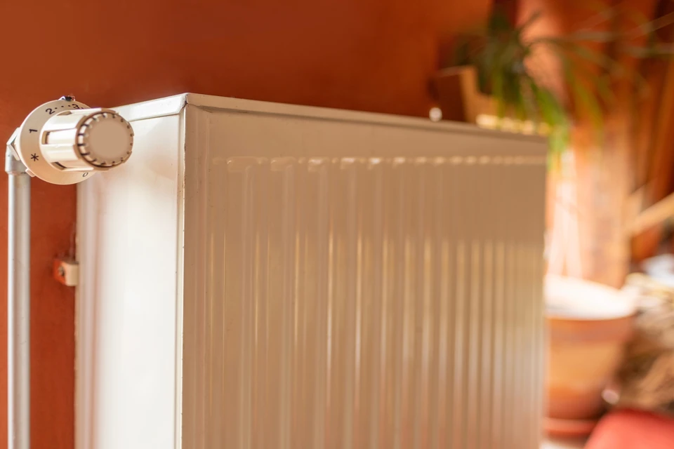 Intérieur résidentiel, technicien en combinaison bleue installant un radiateur blanc mural