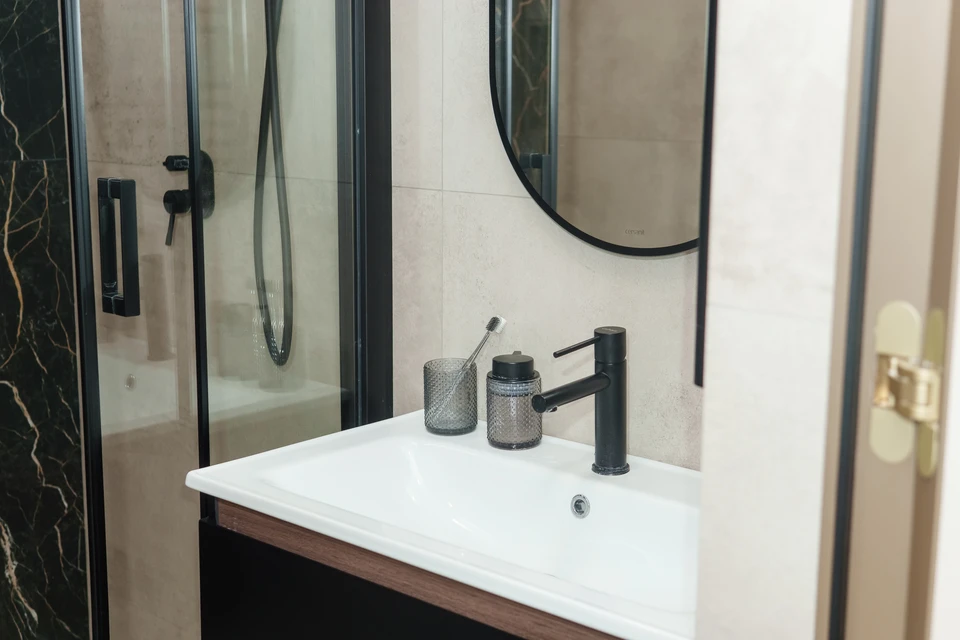 Salle de bain moderne haut de gamme avec douche à l'italienne carrelée anthracite, vasque encastrée en marbre blanc veiné sur meuble suspendu en bois naturel
