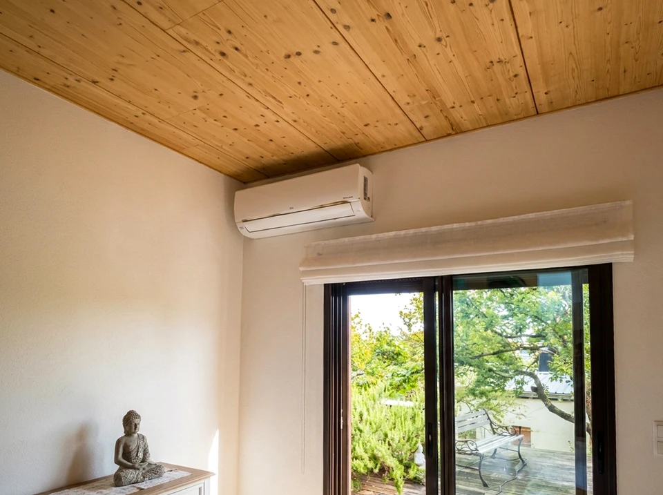 Plombier professionnel en salopette bleue et casque blanc installant un système de chauffage dans un bâtiment en rénovation