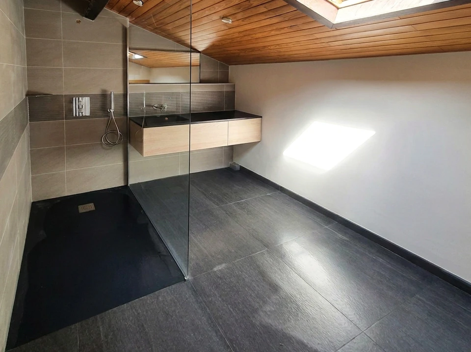 Plombier en salopette grise travaillant dans une salle de bain moderne, installant ou réparant des toilettes blanches
