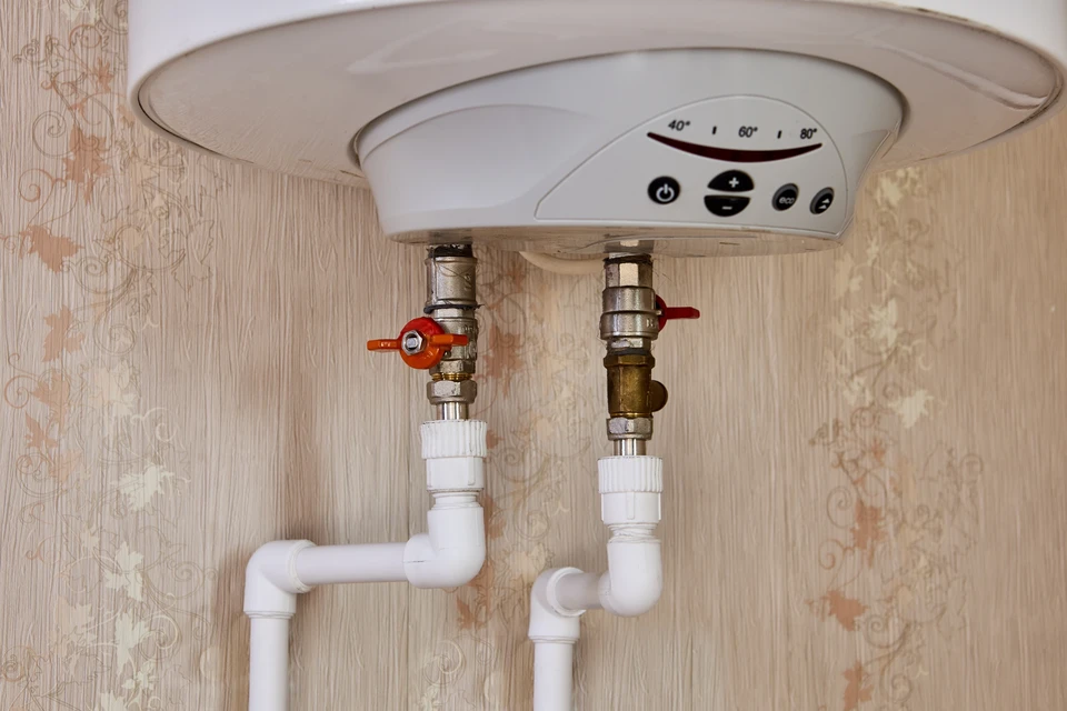 Local technique avec chaudière murale grise et ballon d'eau chaude sanitaire cylindrique équipé de raccordements cuivre